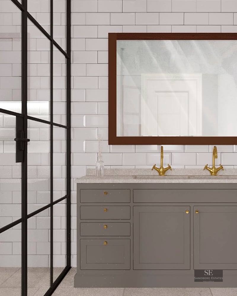 Modern bathroom with a gray double vanity, gold faucets, and a black-framed glass shower against white subway tiles.