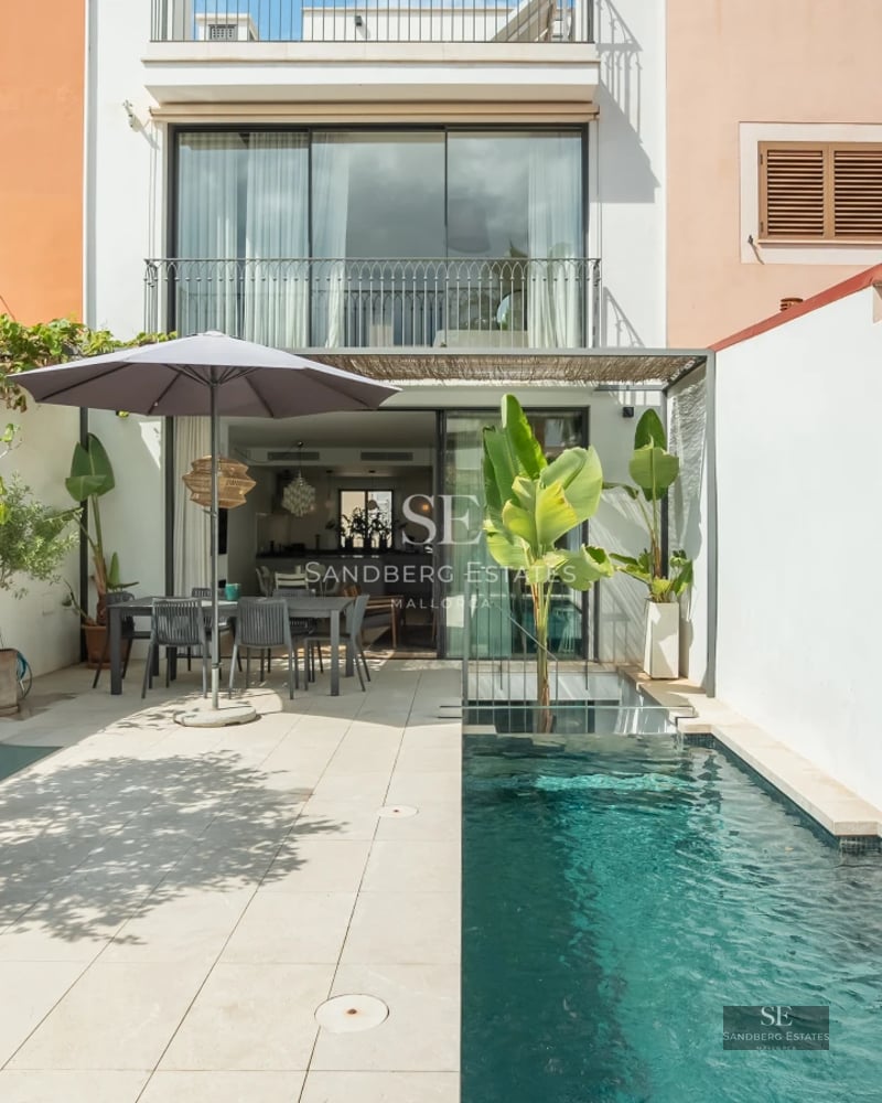 Garden view featuring a pool, modern sun loungers, and lush greenery. Stylish landscaping with ambient lighting.