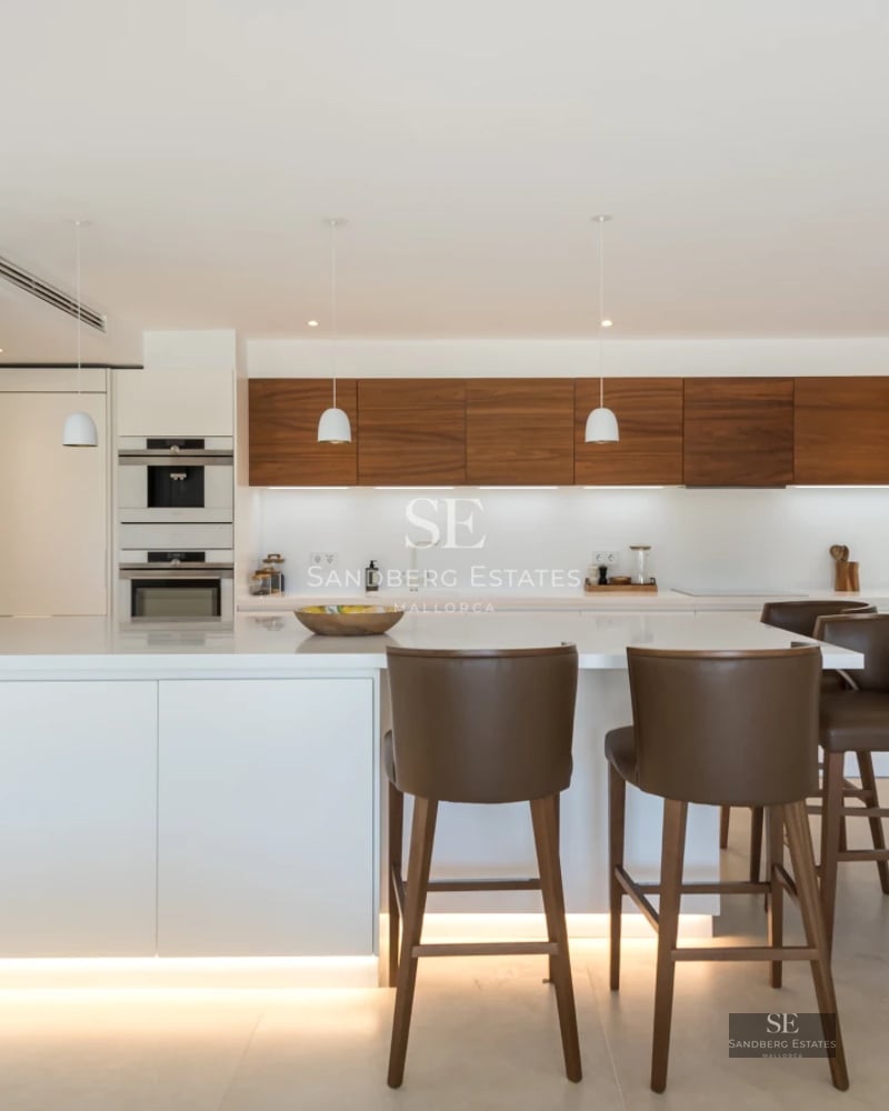 Exterior view of a modern villa with a pool, lush gardens, and expansive windows illuminating the interior.
