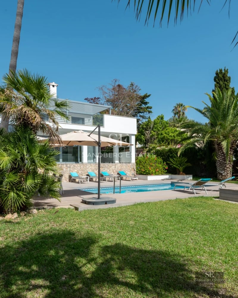 Bright apartment interior with balcony overlooking the sea. Modern design, wood flooring, elegant furnishings, and neutral color palette.