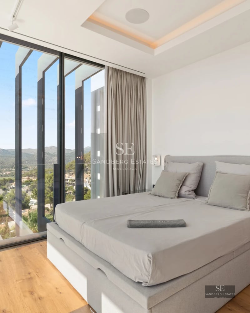 Spacious living room with panoramic windows, natural light, light wood floors, and contemporary furniture. View of the lush garden.