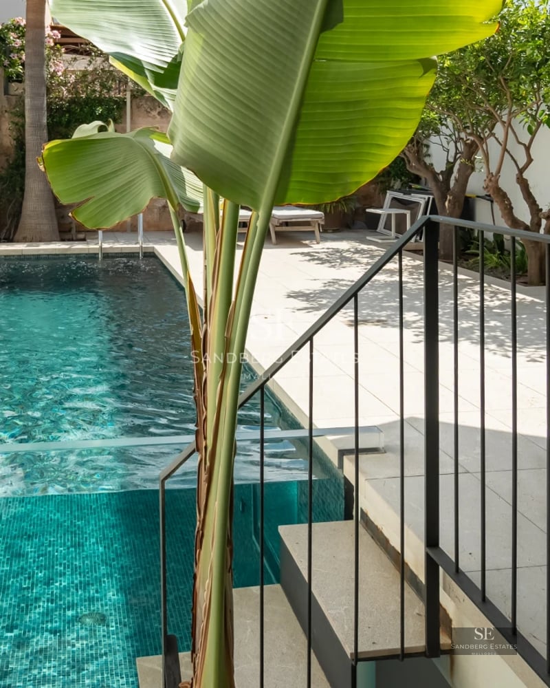 Exterior of a modern villa featuring an infinity pool, expansive terraces, lush vegetation, and panoramic sea views. Minimalist architecture.