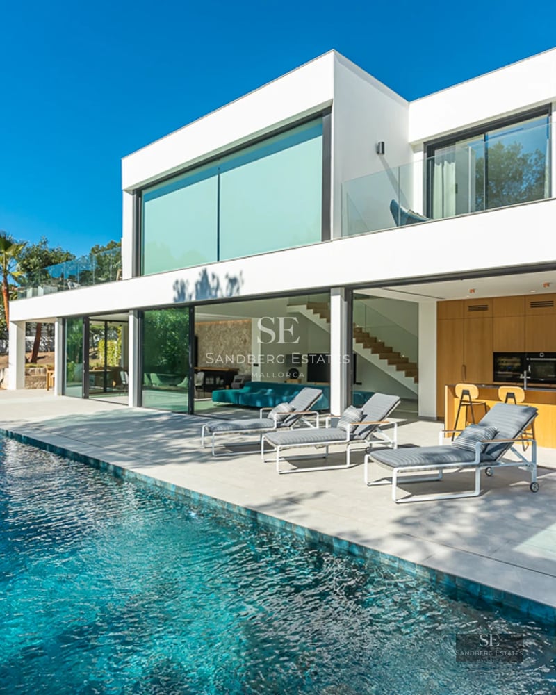 Extérieur d'une villa moderne avec piscine, pelouse et grandes baies vitrées. Design minimaliste aux lignes épurées et lumière naturelle abondante.