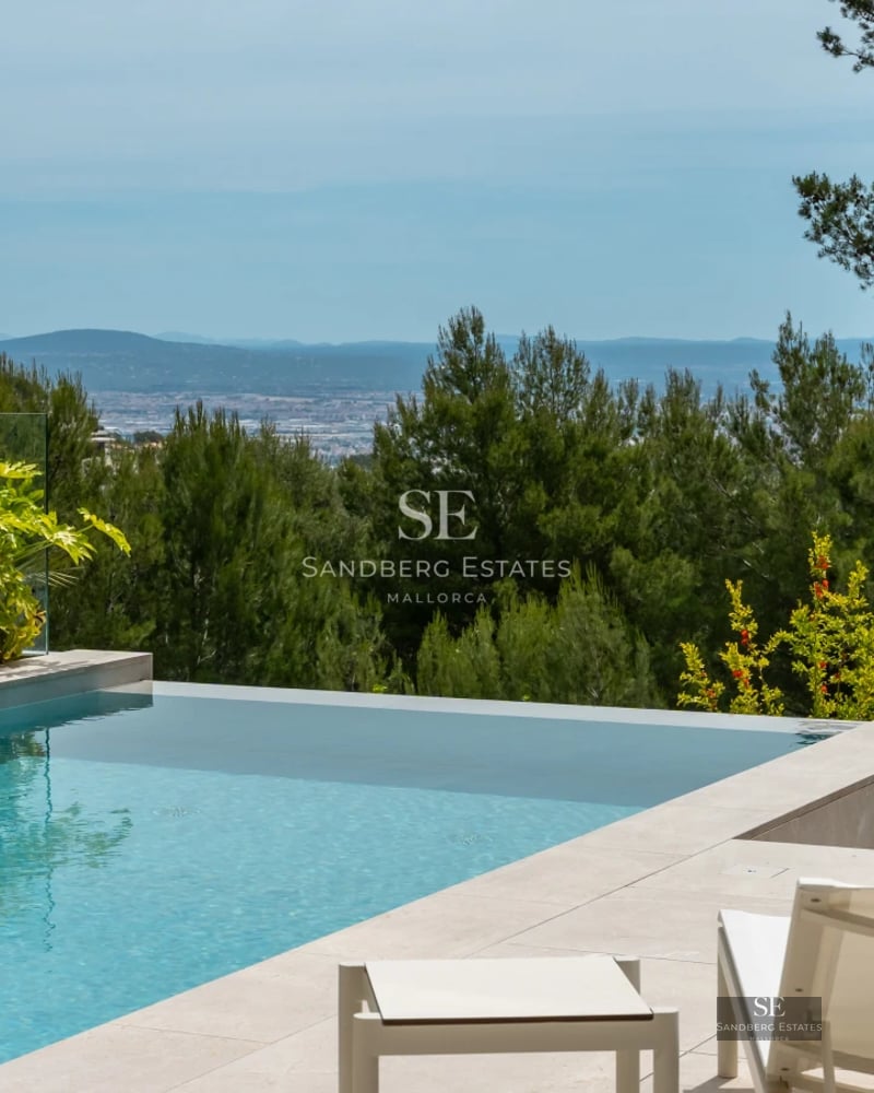 Spacious balcony with panoramic sea views. Modern design, glass railing, and stylish furniture. Warm lighting and wooden flooring.