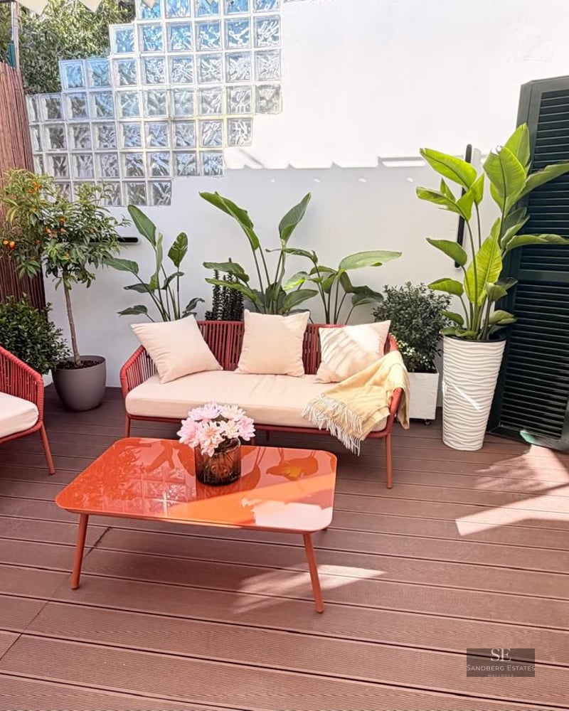 Terrace featuring wood decking, terracotta-colored outdoor furniture, and decorative plants under bright natural light.