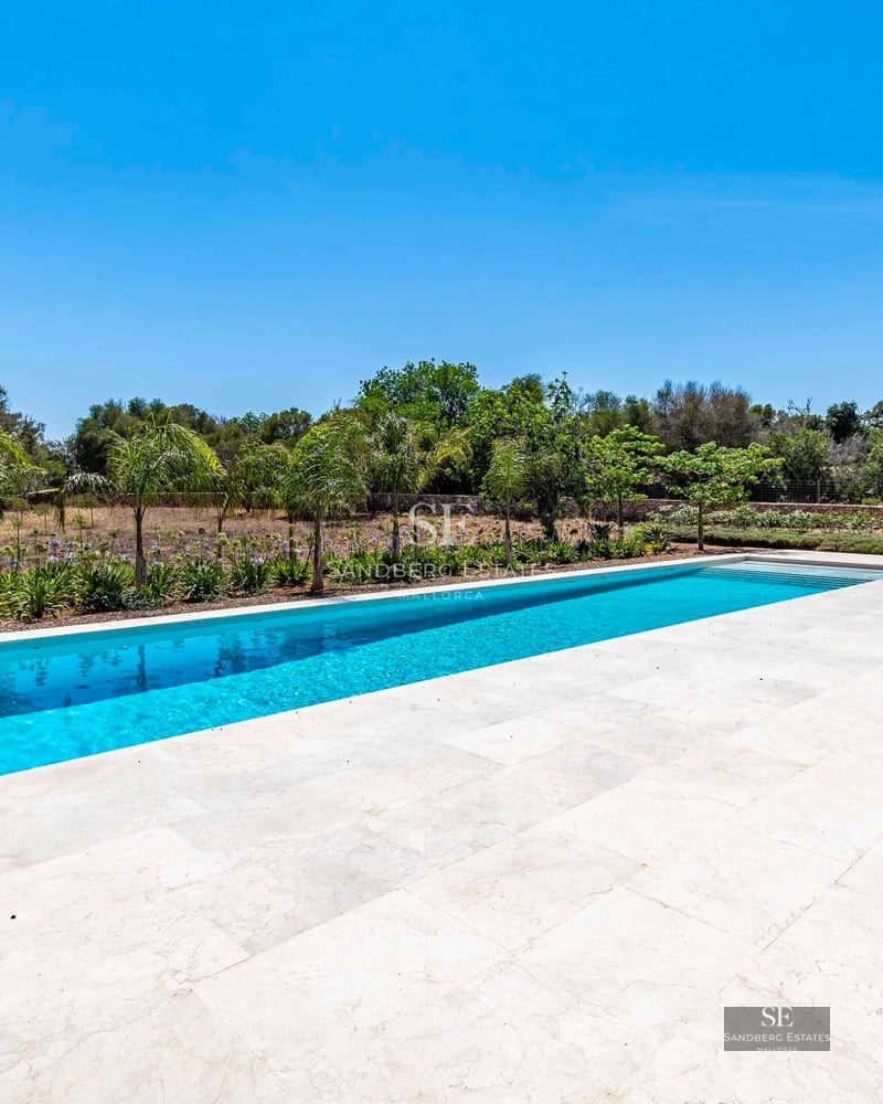 Exterior view of a modern villa with pool, surrounded by a garden and featuring large windows. Minimalist architecture and lush landscaping.