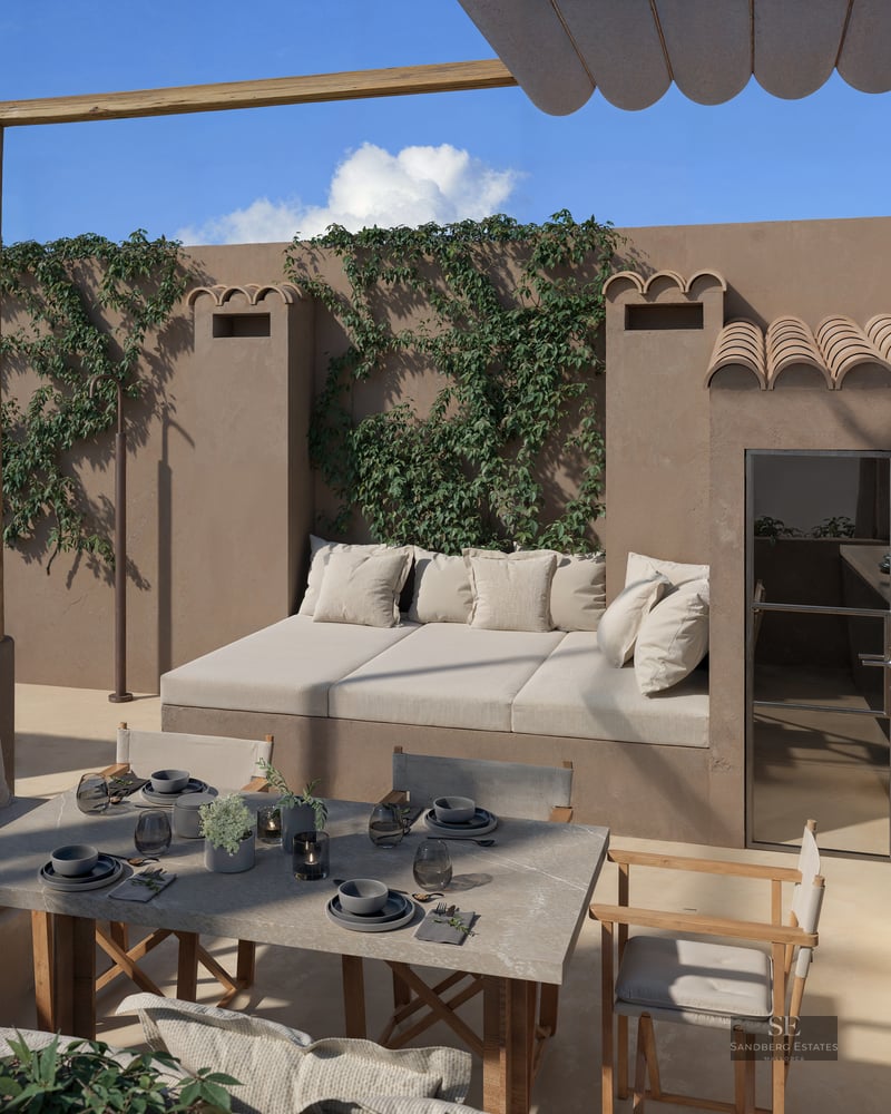 Sun-drenched rooftop terrace with a stone dining table, integrated daybed, outdoor kitchen, and climbing vines on stucco walls.