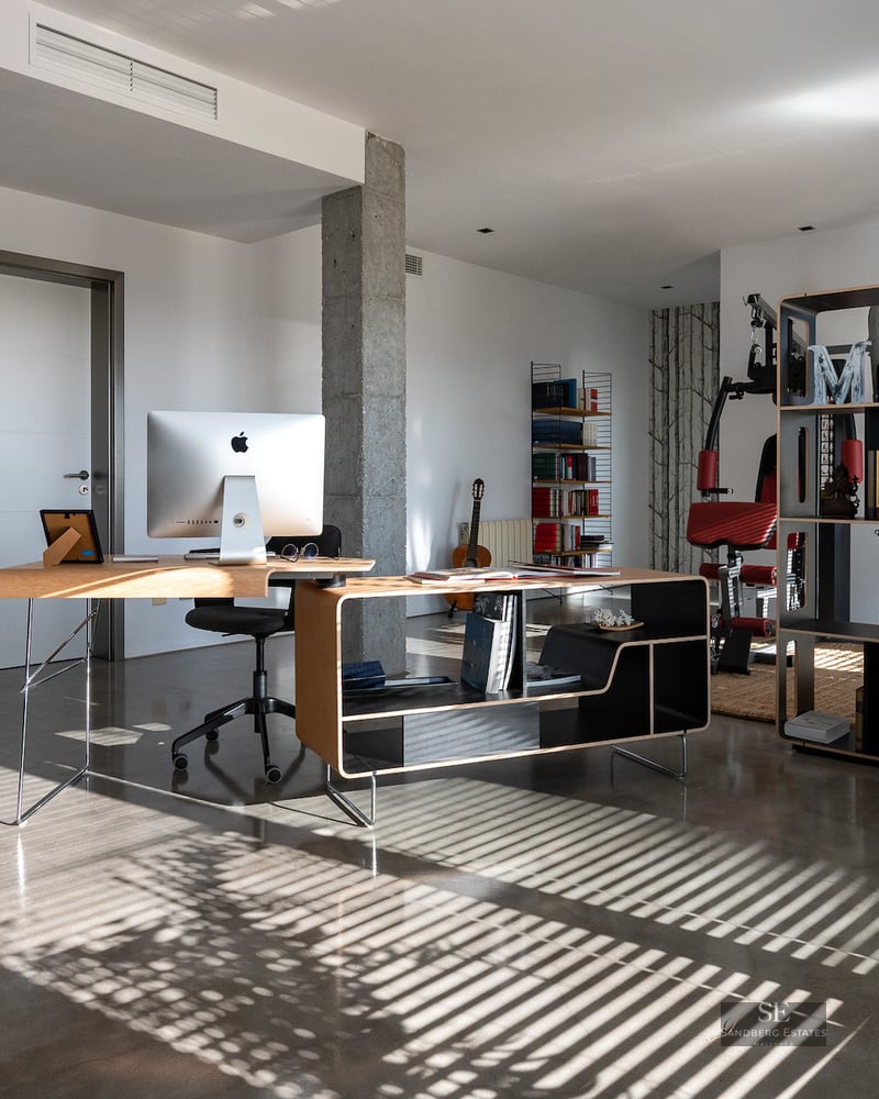 Bright home office featuring a designer wooden desk, iMac, polished concrete floors, and a bookshelf.