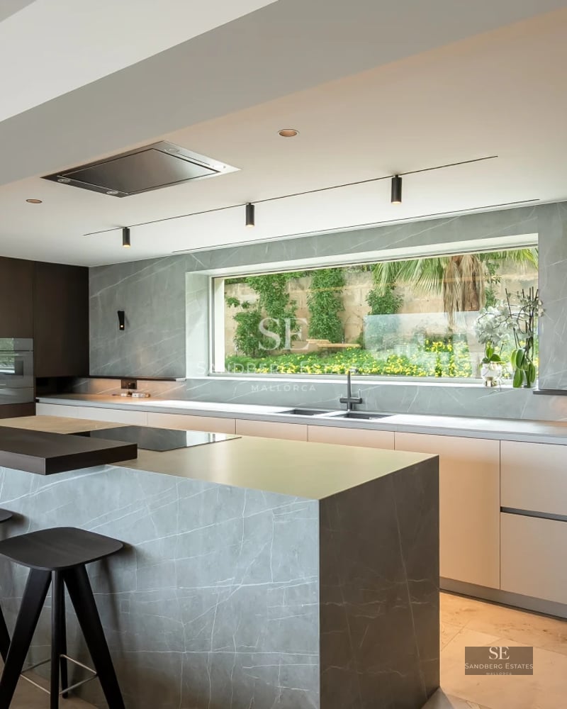 View of an infinity pool with sun loungers, a wooden deck, and a modern house with large windows. Luxury and tranquility.