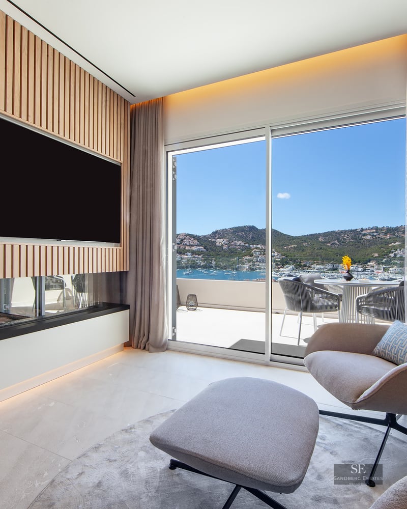 Contemporary lounge featuring an armchair, fireplace, wood-slat TV wall, and panoramic harbor views through sliding doors.