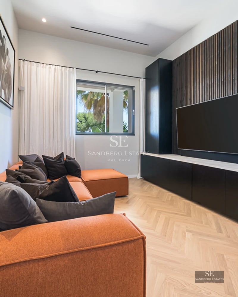 Salon spacieux avec de grandes baies vitrées, canapés gris, table basse moderne et vue imprenable sur la mer. Abondance de lumière naturelle.