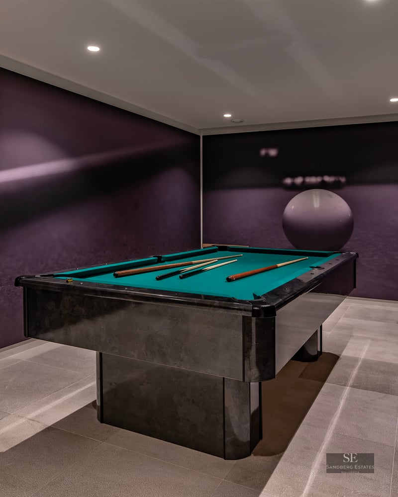 Modern game room featuring a black pool table with green felt and large pool-themed wall murals.