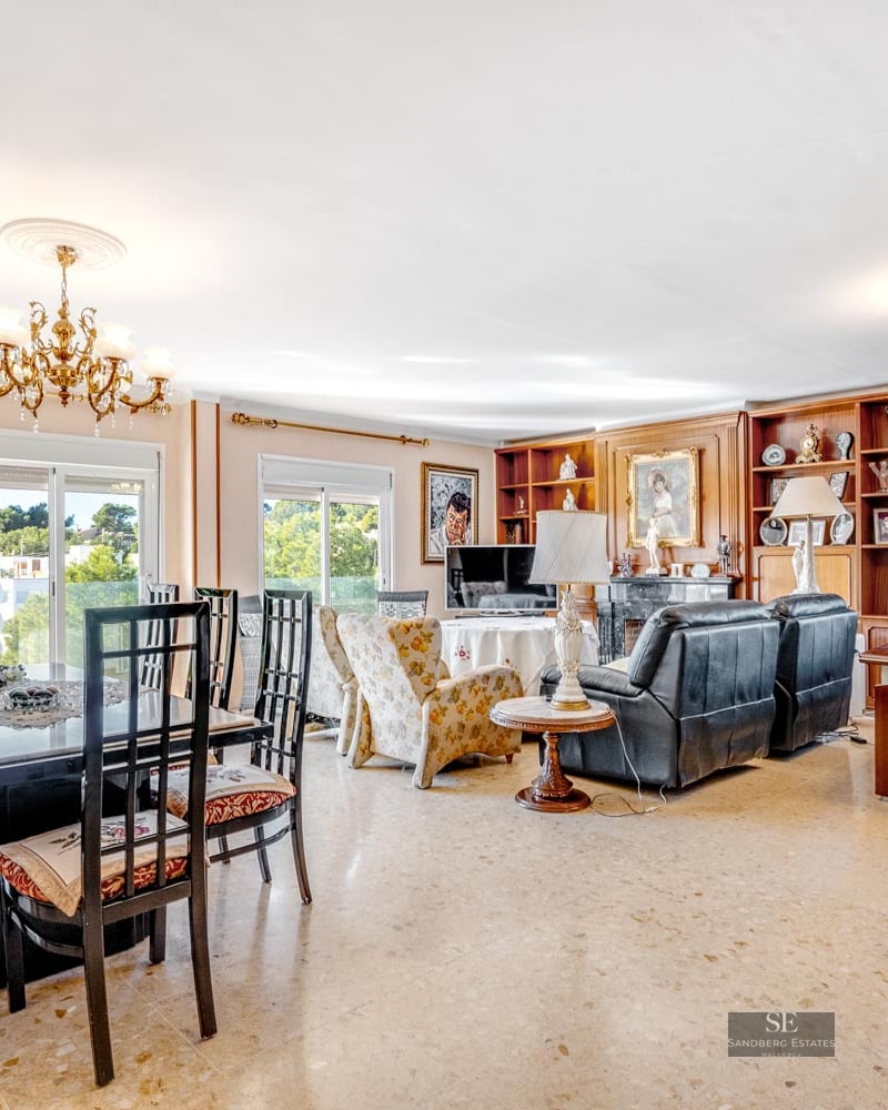 Bright open-plan living room with marble floors, dining set, black leather recliners, and a home office corner.