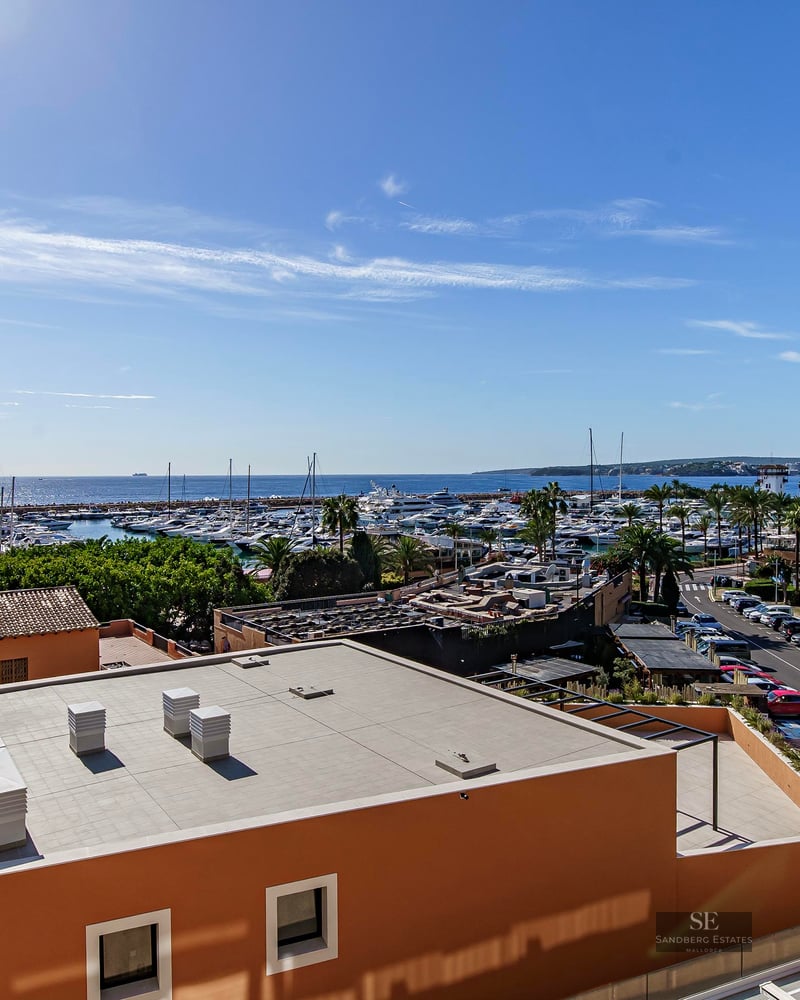 Elevated view overlooking a marina with yachts and the Mediterranean sea under a clear blue sky.