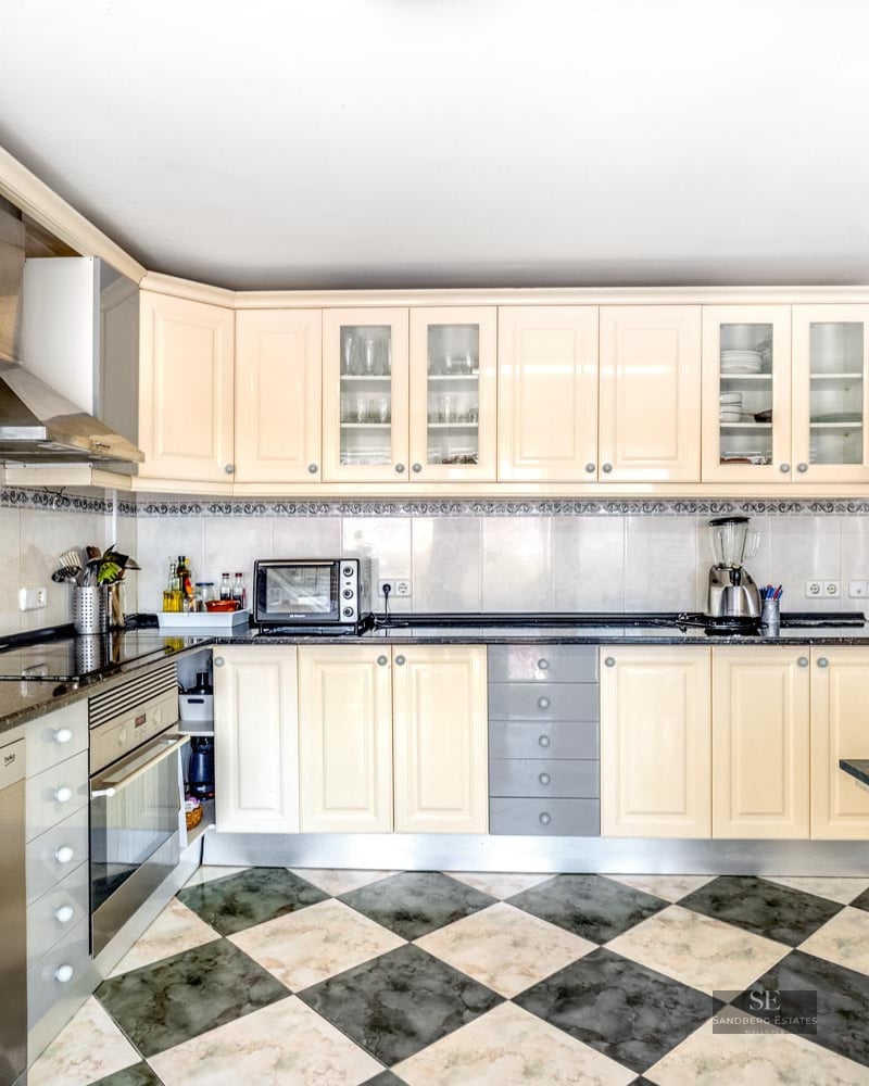 Bright kitchen with cream cabinets, dark granite countertops, and a green and white checkered tiled floor.