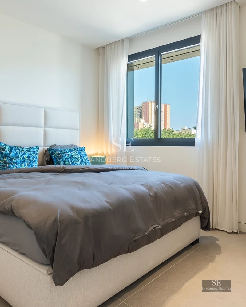 Aerial view of infinity pool surrounded by lawn and sun loungers. Modern house with panoramic windows and covered terrace.