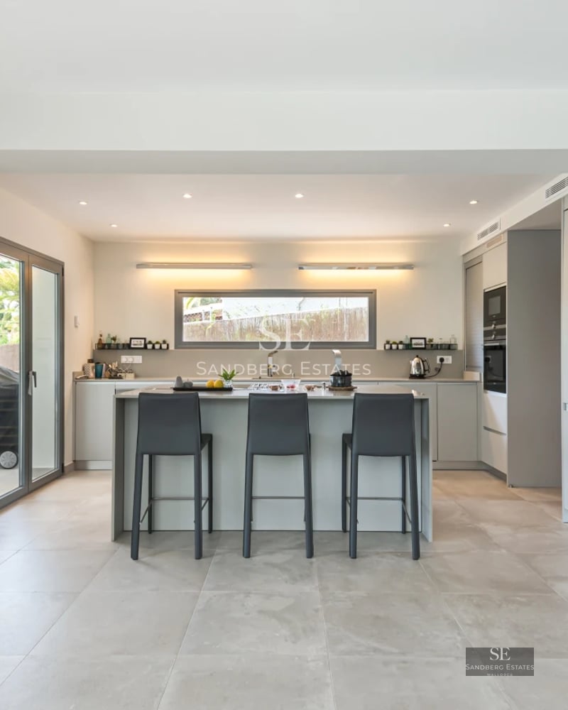 Bright living room with sea view, balcony, wood floors, and modern decor. Large windows and designer furniture.