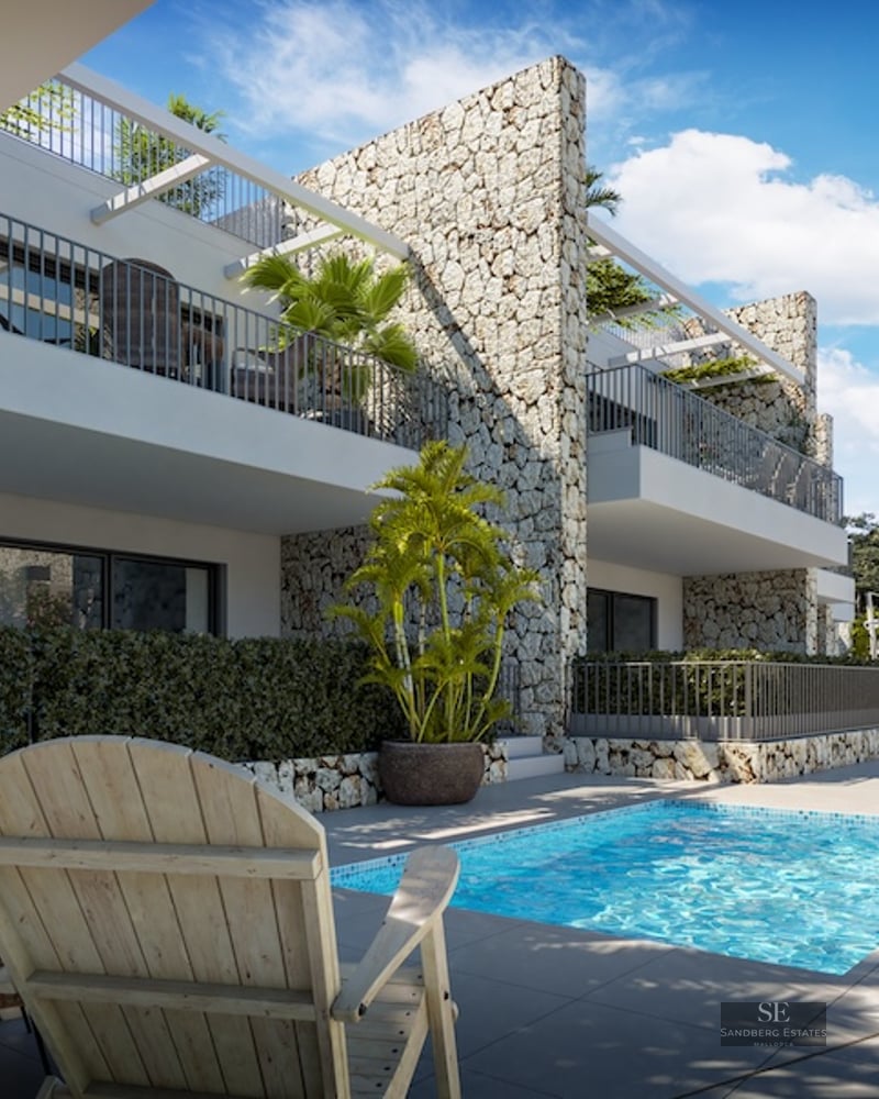 Modern swimming pool with wooden loungers and stone feature walls under a clear blue sky.