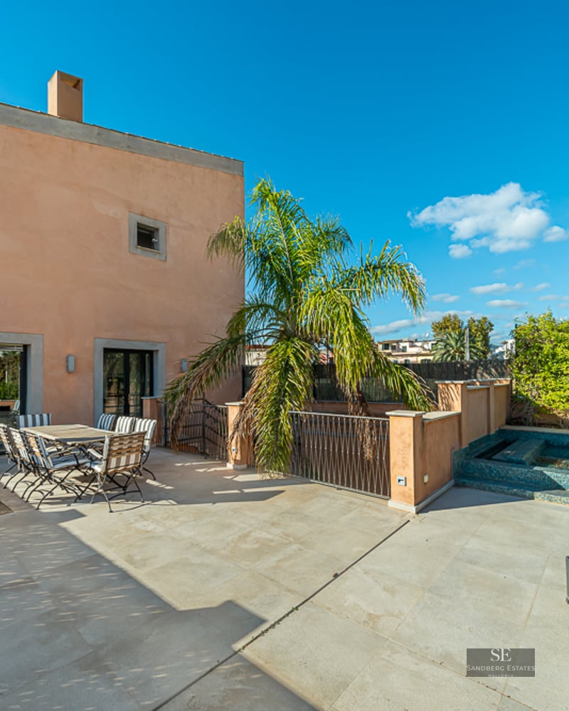 Mediterranean terrace with stone tile flooring, outdoor dining set, a palm tree, and a small tiled plunge pool under a clear blue sky.