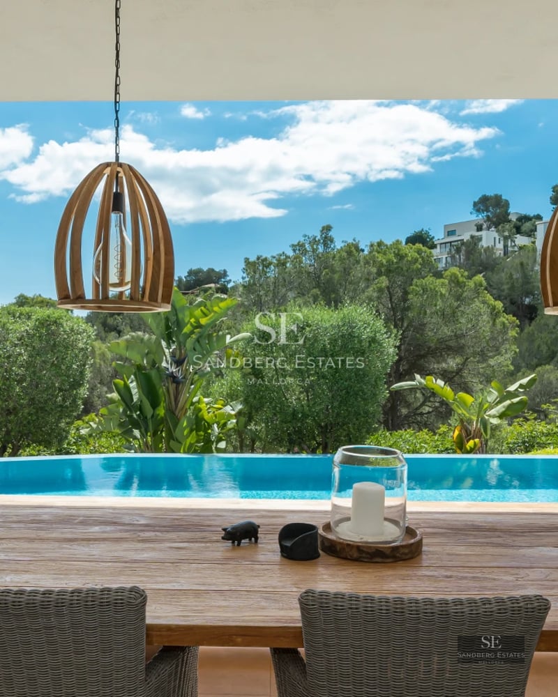 Exterior of a modern villa with a pool, outdoor living area, and lush greenery. Minimalist and elegant design.