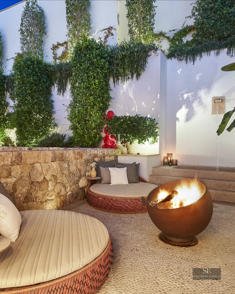 Spacious living room with fireplace, picture windows, and designer furniture. Warm, natural lighting. Wooden floors and light walls.