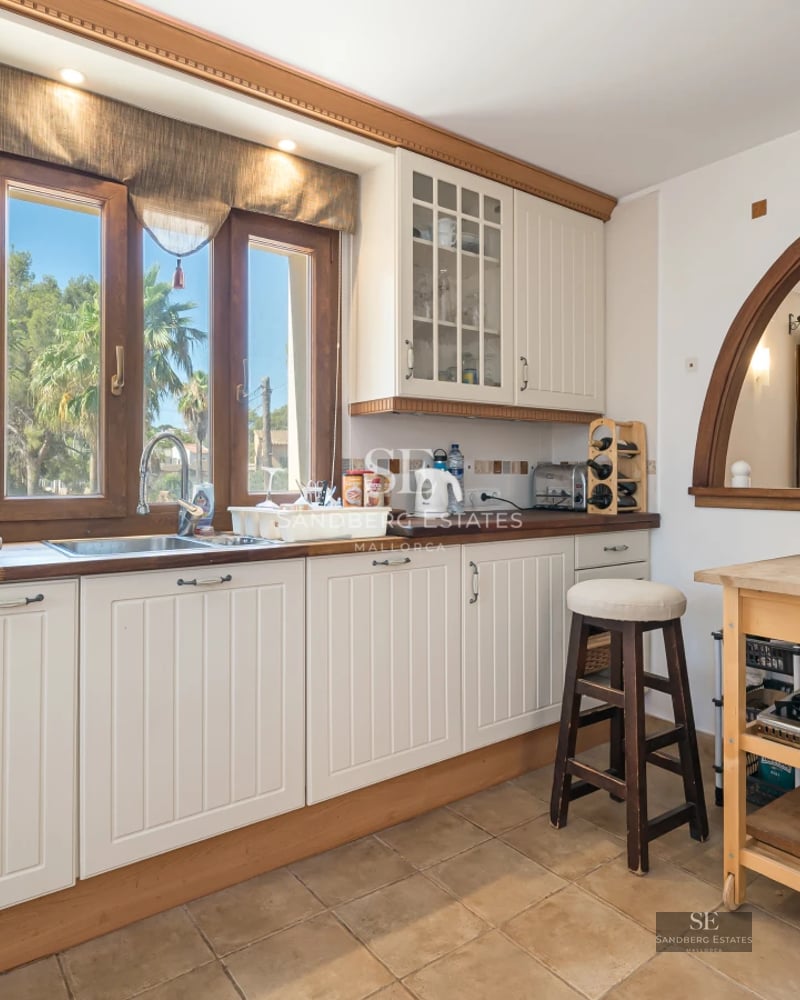 View of a modern villa featuring an infinity pool, lush garden, and minimalist architecture. Large windows illuminate the interior.