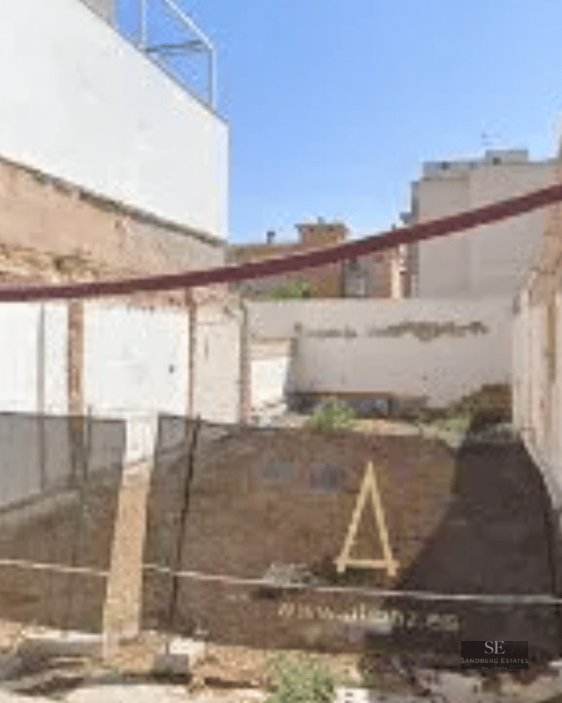 View of a construction site with safety fencing and visible white perimeter walls.