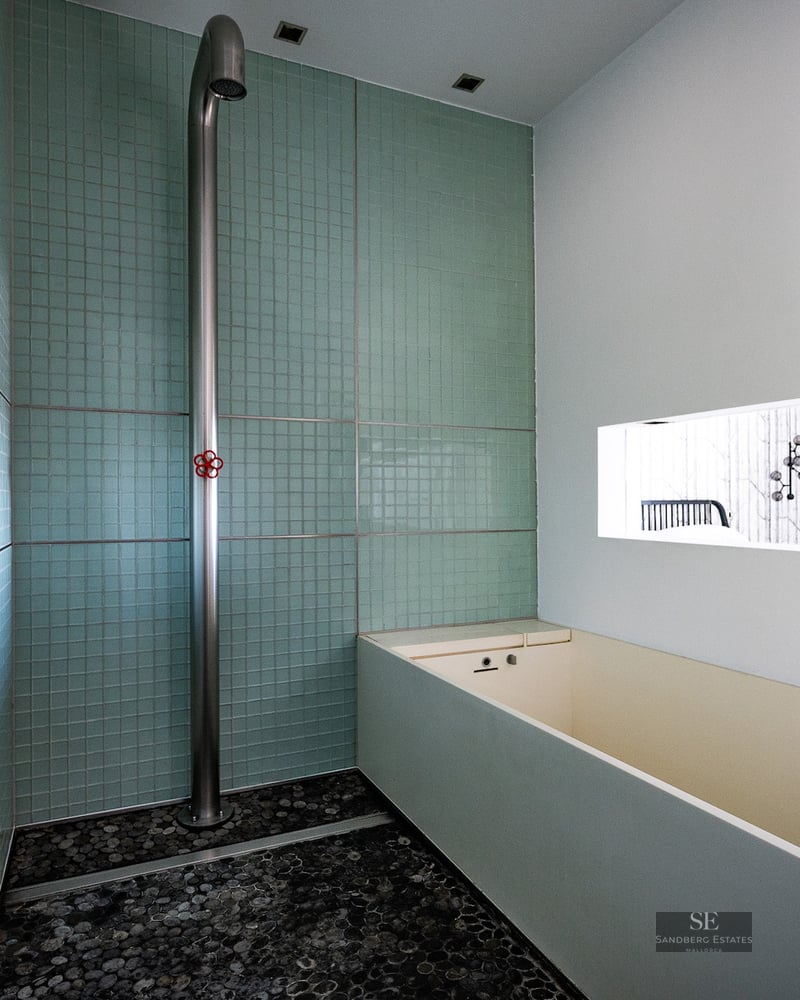 Modern wet room featuring mint green mosaic tiles, a minimalist stainless steel shower, and a pebble floor.