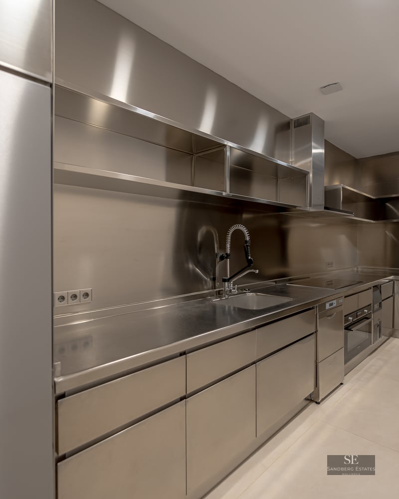 Modern industrial kitchen featuring high-end stainless steel cabinets, countertops, and a professional-grade faucet.