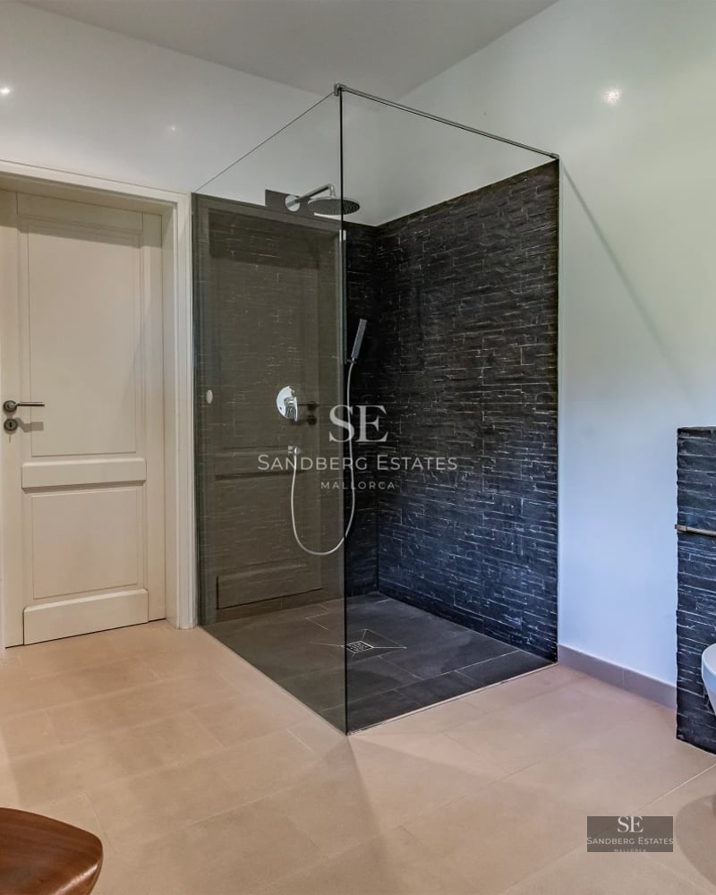 View of infinity pool with terrace, sun loungers, and lush garden. Modern architecture and elegant design with large glass windows.