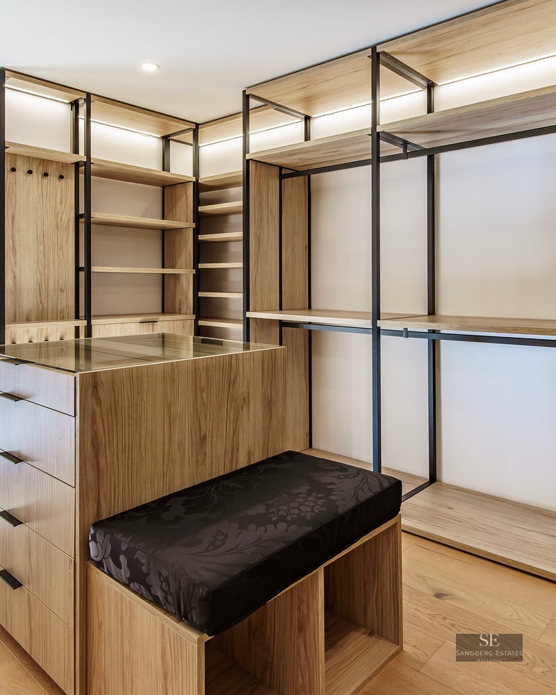 Dressing moderne avec étagères en bois clair, cadres en métal noir, un îlot central et accès au balcon.