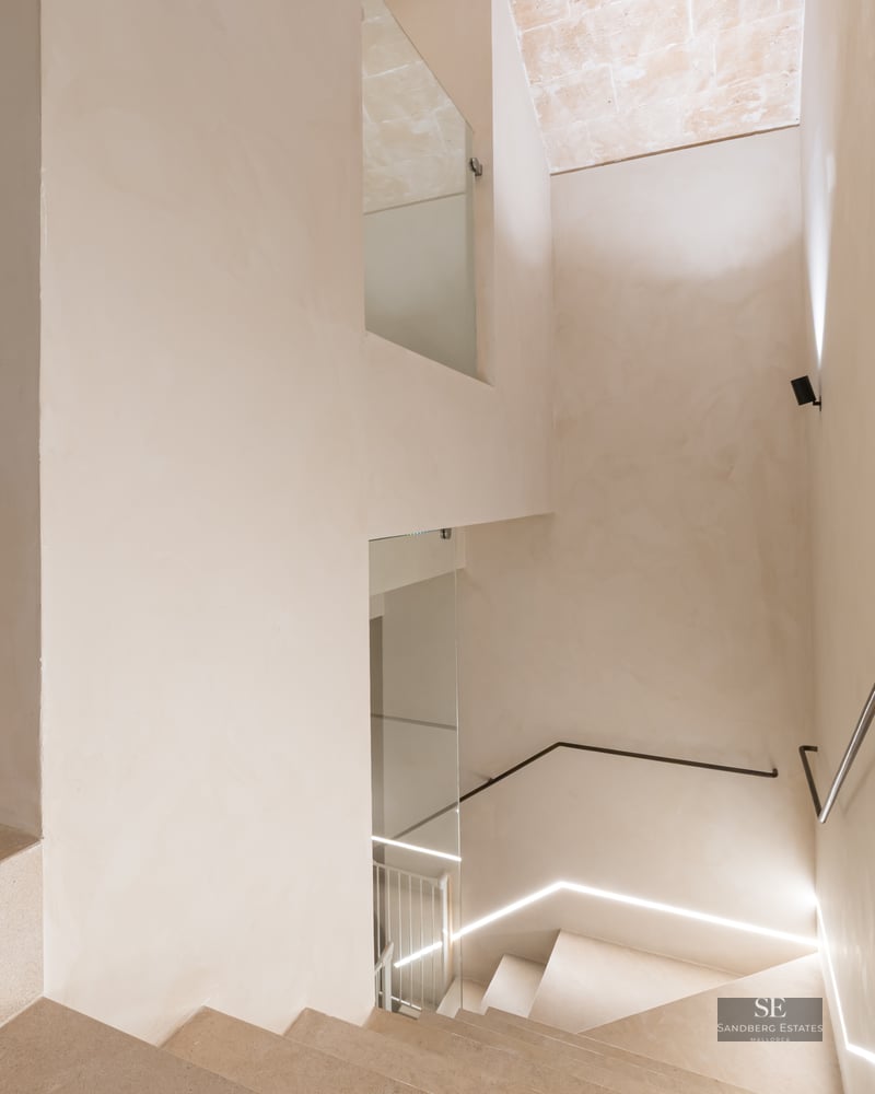 Minimalist design stone staircase with a slim metal handrail and integrated LED floor lighting.