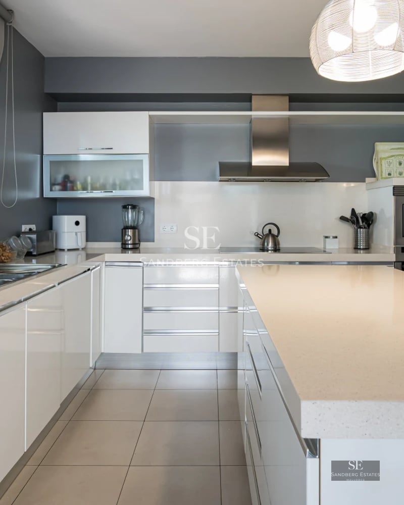 Exterior view of a modern villa featuring an infinity pool, furnished terrace, and lush greenery. Contemporary architectural design.