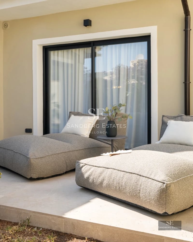 Spacious balcony with sea views, glass railing, modern furniture, and light wood floors. Warm ambient lighting.