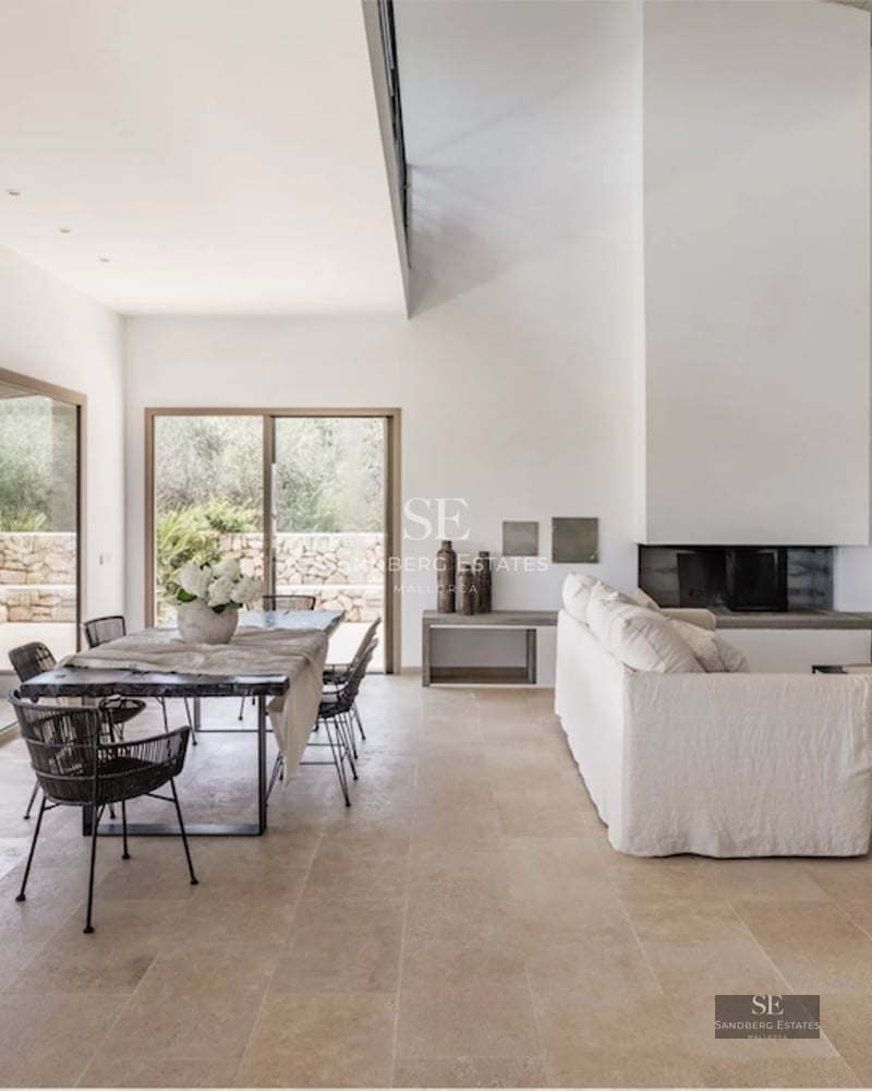 View of a luxury villa featuring an infinity pool, surrounded by lush gardens and expansive terraces. Modern design with window walls and natural stone.