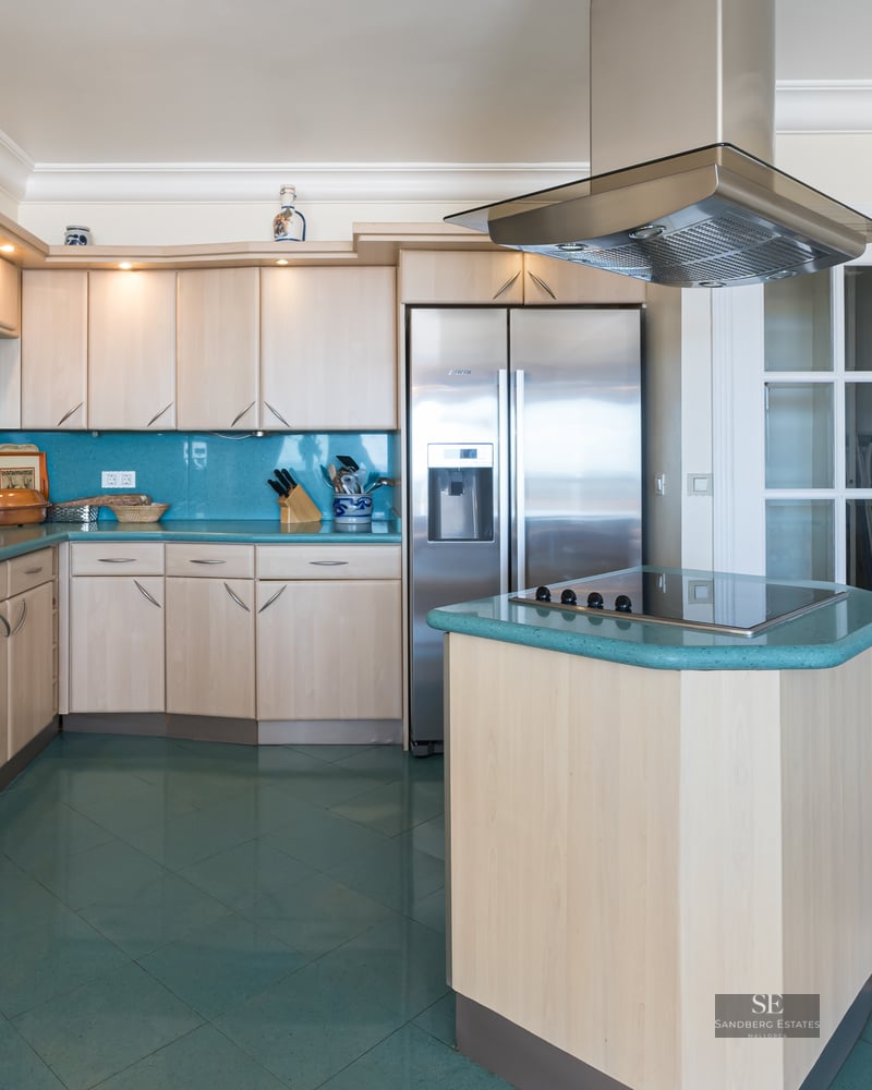 Contemporary kitchen with light wood cabinets, turquoise countertops and floors, and stainless steel appliances.