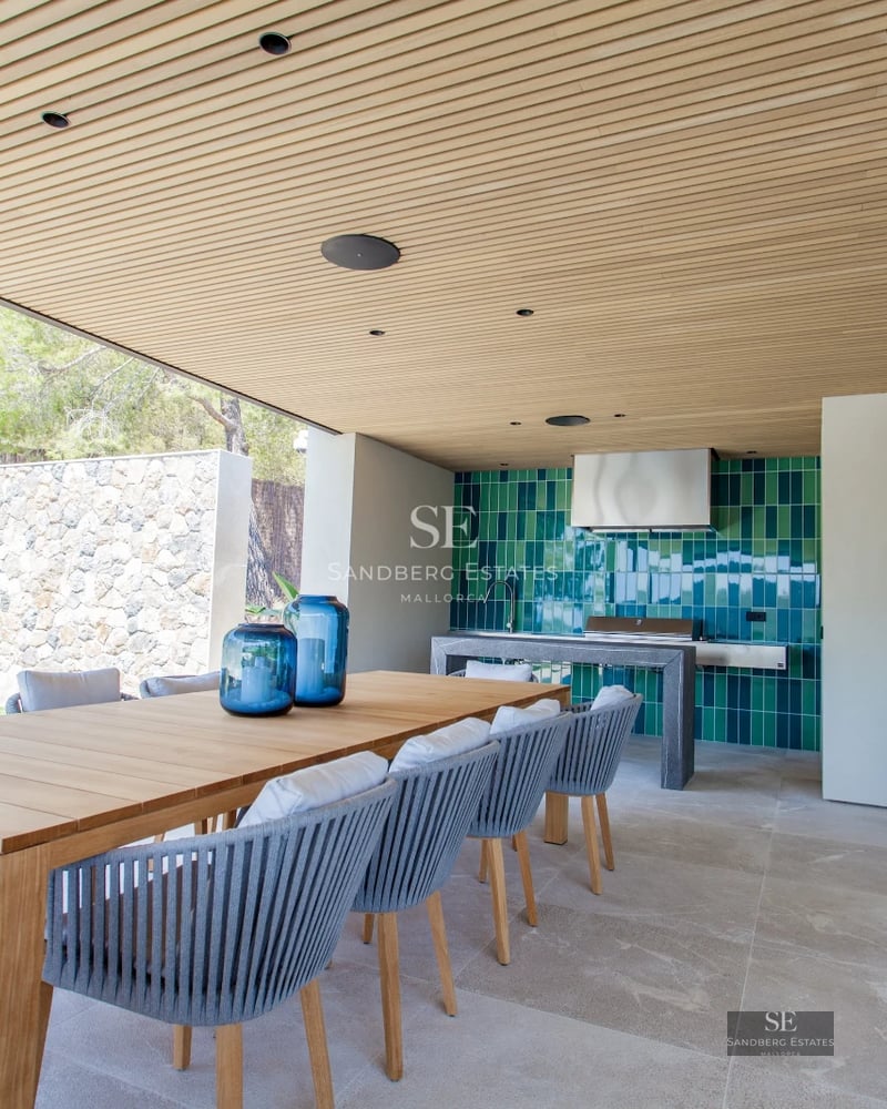 Panoramic view of a modern living room with a balcony, stylish furniture, wooden floors, and large windows offering stunning sea views.