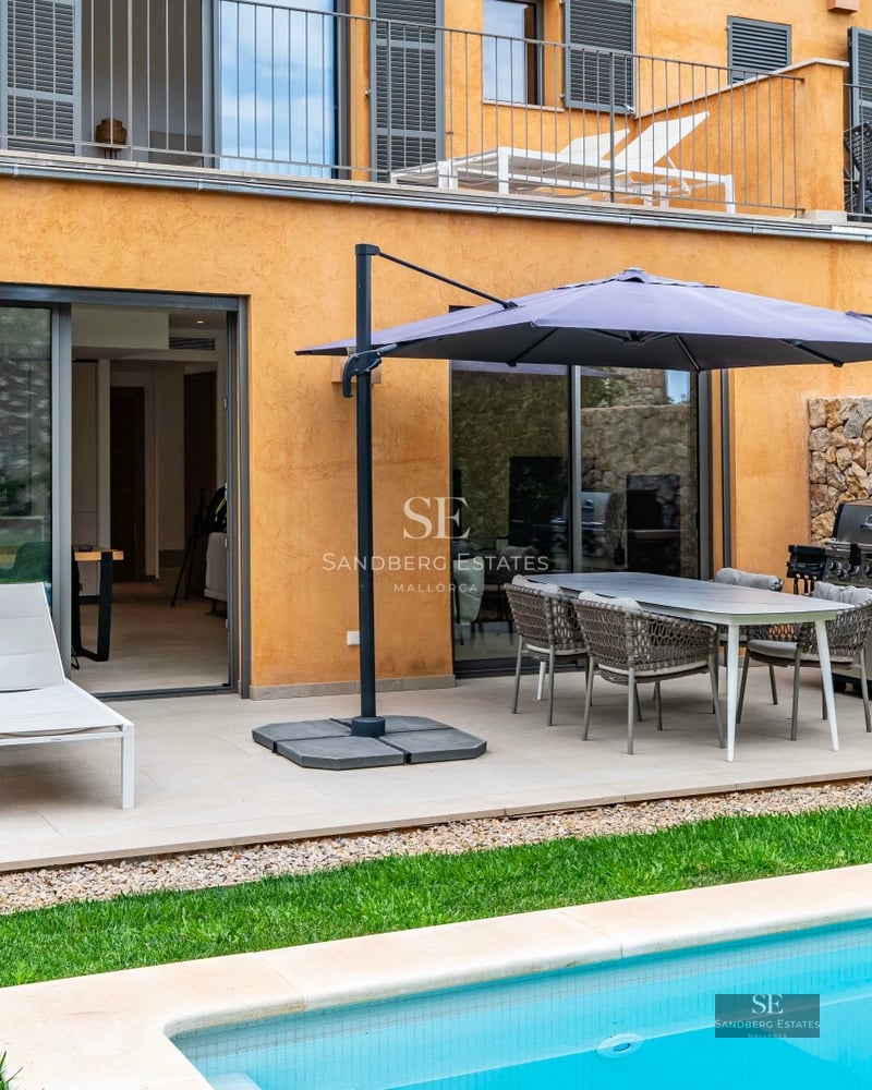 Exterior view of a luxurious, modern villa featuring a pool, manicured garden, and expansive terraces. Minimalist and bright architecture.