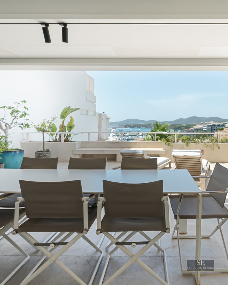 Modern terrace with outdoor dining area, BBQ, and panoramic views of the coastal town and sea.