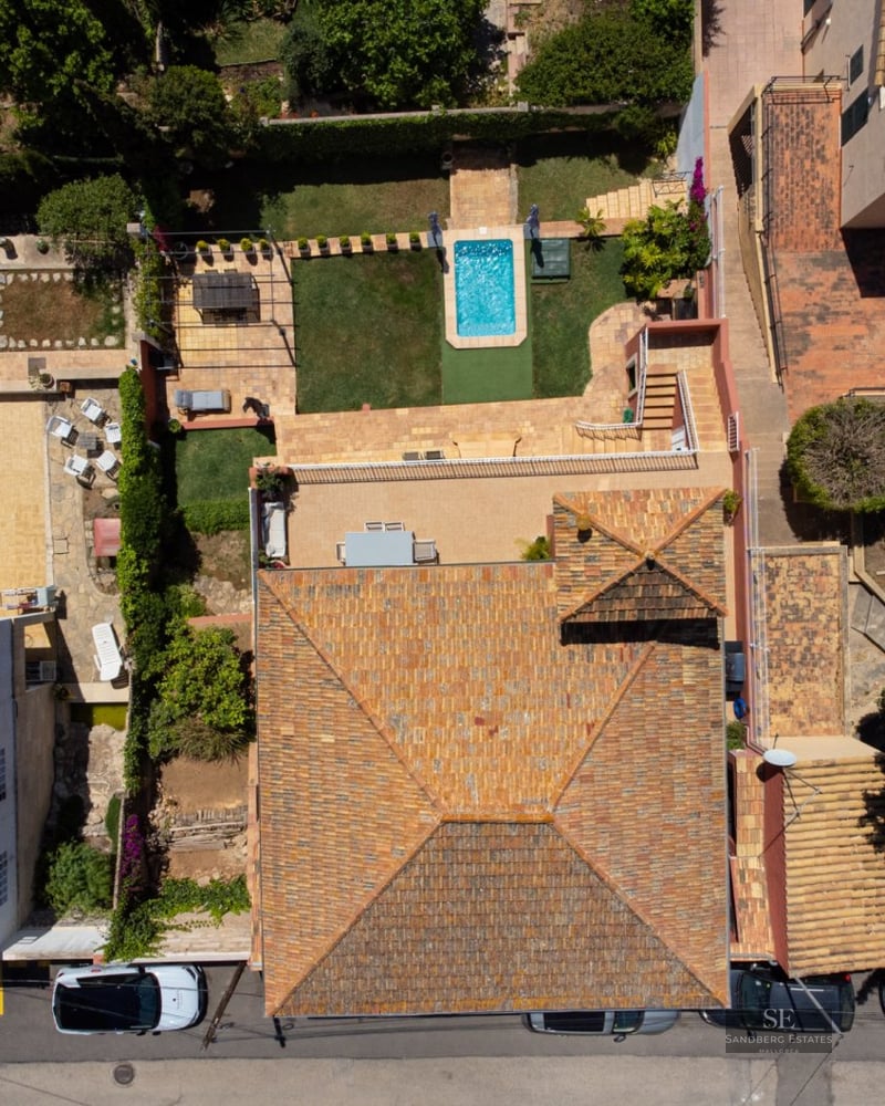 Aerial top-down view of a Mediterranean house with a tiled roof, small swimming pool, and landscaped garden.