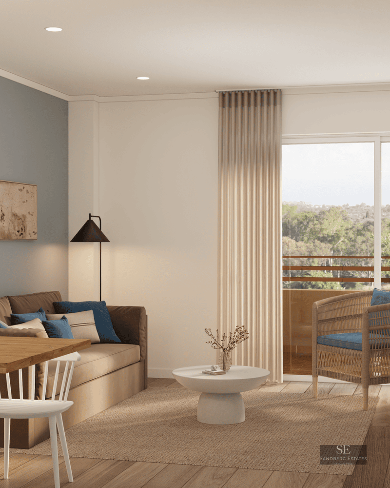 Salon moderne avec canapé beige, mur bleu, table en bois et grande baie vitrée donnant sur les arbres.