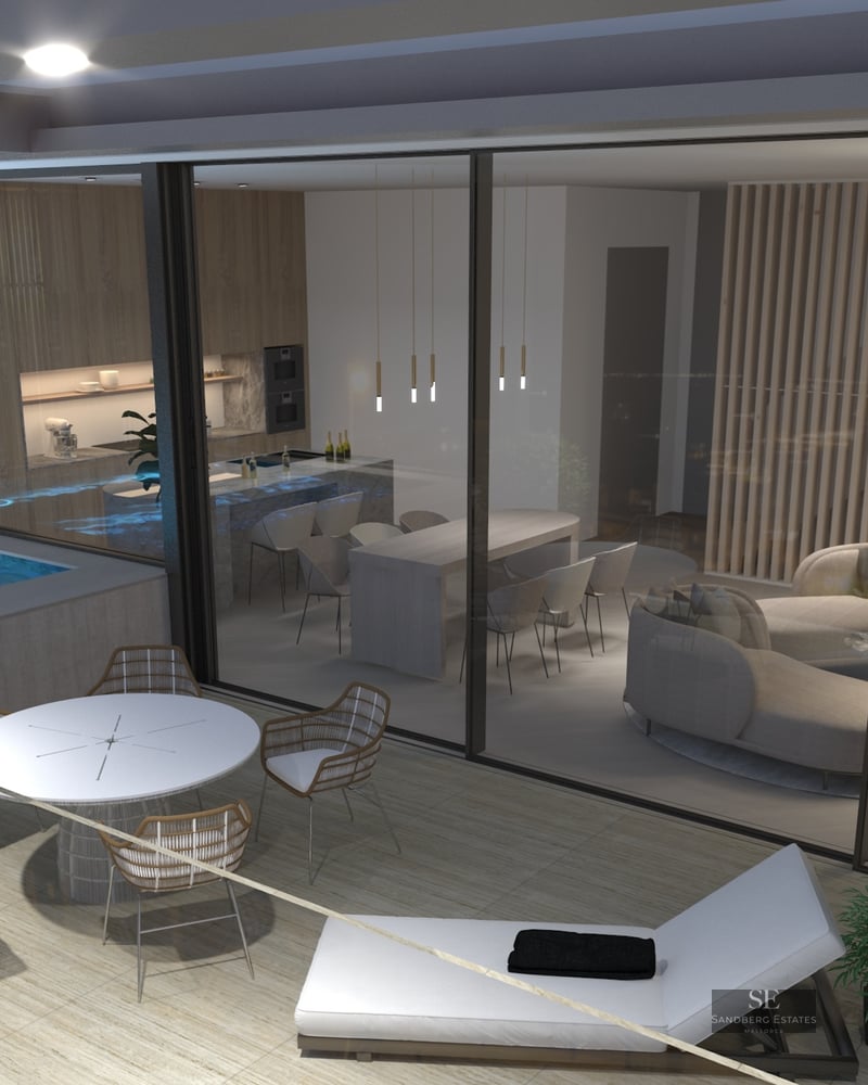 Evening view of a modern terrace with outdoor dining, sun lounger, and a glowing blue plunge pool by glass doors.