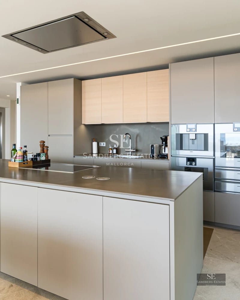 Spacious living room with floor-to-ceiling windows, sea view, light wood floors and modern designer furniture. Abundant natural light.