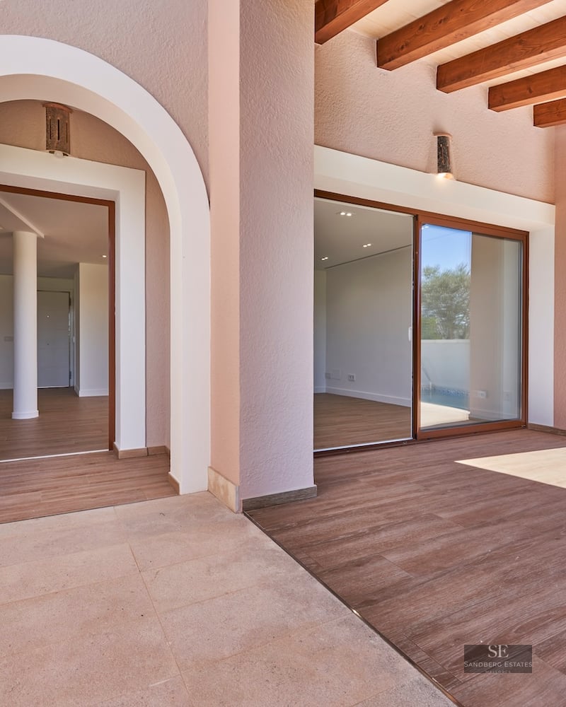 Covered terrace with stone floors, wooden beams, an arched entry, and a pool on the right side.