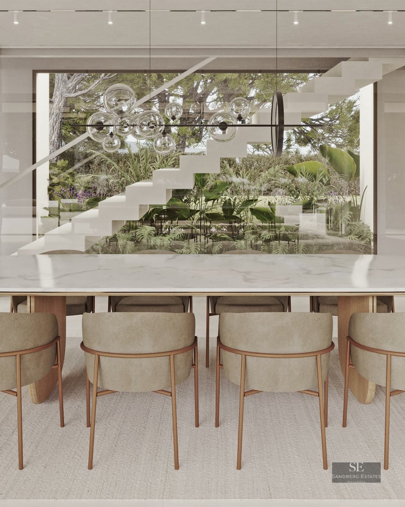 Elegant dining area featuring a white marble table, stone pillars, and views of a designer staircase and lush garden.