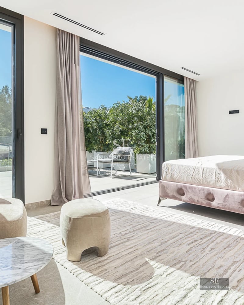Vaste piscine bordée de carreaux clairs et de chaises longues. Villa moderne avec de grandes baies vitrées et une végétation luxuriante.