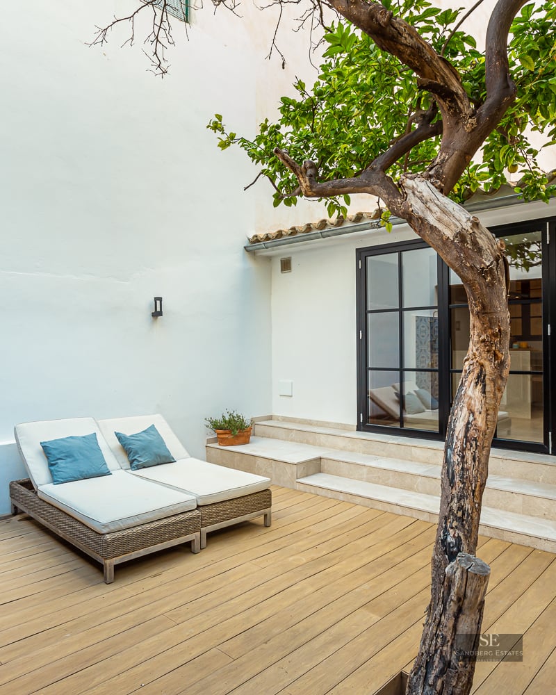 Wooden deck terrace with sun loungers, an outdoor shower with blue patterned tiles, and a mature tree.