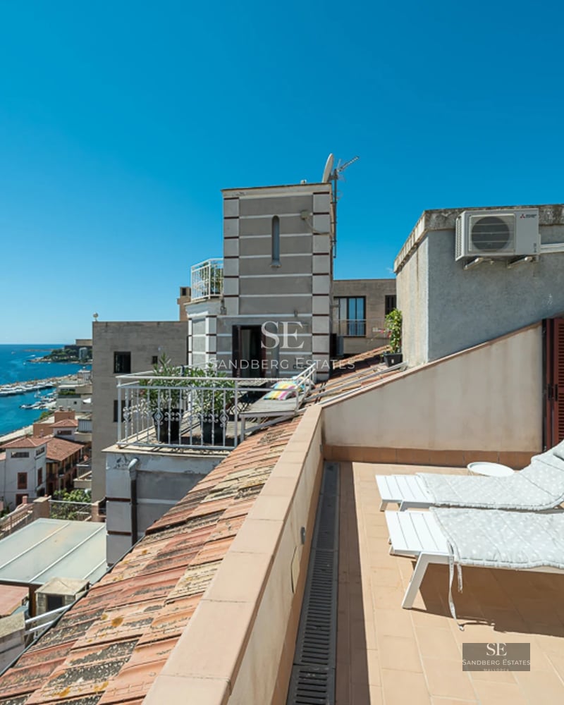 Modern balcony with glass railing, sea view, and minimalist furniture. Elegant design featuring light wood and plants.