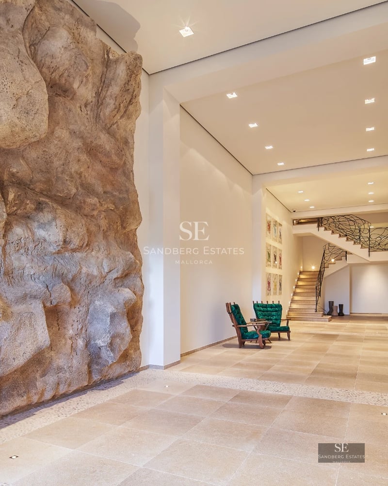 View of an elegant villa with a pool, lush garden, and modern architectural design. Stone details and large windows.