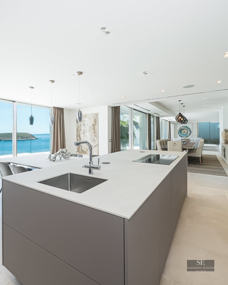 Minimalist kitchen island facing a terrace with expansive ocean views and a distant island.